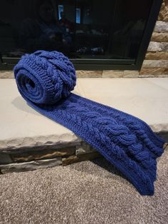 a blue knitted tie sitting on the floor next to a fireplace