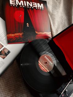 an old record player sitting on top of a bed next to a book and magazine