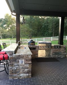 an outdoor kitchen with grill and bar stools