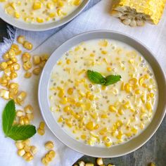 two white bowls filled with corn and topped with green leafy garnishes