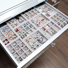 a drawer filled with lots of jewelry on top of a wooden floor