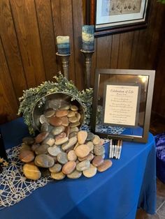 a blue table cloth with rocks and candles on it in front of a framed plaque