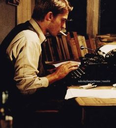 a man sitting at a desk typing on an old typewriter