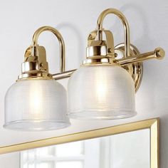 two light bathroom fixture with white glass shades on the bottom and gold trimmings