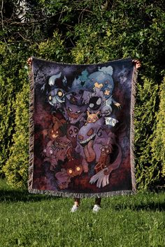 a person standing in the grass holding up a blanket with an image of monsters on it