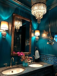 a bathroom with two sinks and a large mirror above it in front of a chandelier