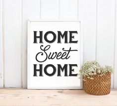 a sign that says home sweet home next to a potted plant on a shelf