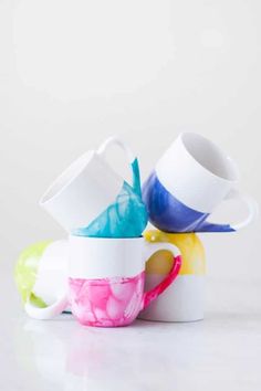 four cups stacked on top of each other in different colors and shapes, with the lids slightly open