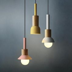 three different colored lights hanging from the ceiling in a room with grey walls and flooring