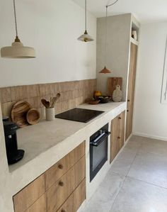 a kitchen with wooden cabinets and white counter tops, along with hanging lights above the sink