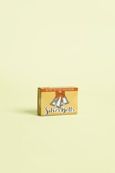 a box of silver bells sitting on top of a white table next to a red apple