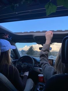 two people driving in the back seat of a car with their hands on the steering wheel