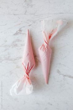 two candy cones wrapped in pink paper on a marble surface