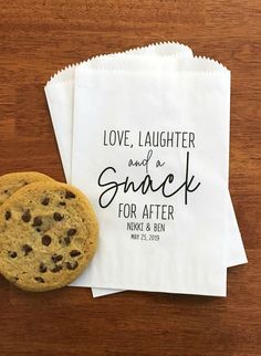 two personalized wedding favors and one chocolate chip cookie on a wooden table with napkins