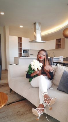 a woman sitting on top of a couch holding flowers