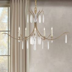 a chandelier hanging from a ceiling in front of a window with white curtains