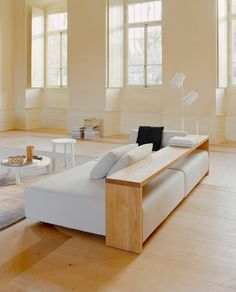 a white couch sitting on top of a hard wood floor next to two large windows