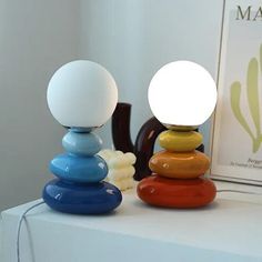 two colorful lamps sitting on top of a white table