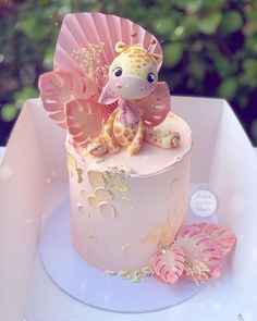 a pink cake with a giraffe decoration on top