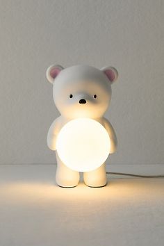 a small white teddy bear holding a light