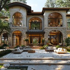 an outdoor living area with couches and tables in front of a large stone building