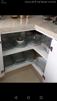 an open cabinet with plates and bowls in it