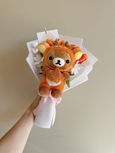 a hand holding a stuffed animal with flowers