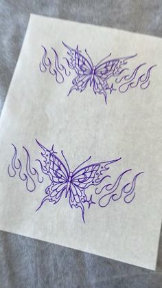 two butterfly tattoos on top of a piece of paper with flames coming out of them