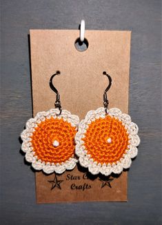 crochet earrings with orange and white flowers on the front, hanging from a card