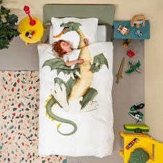 a child laying in bed with a dragon comforter