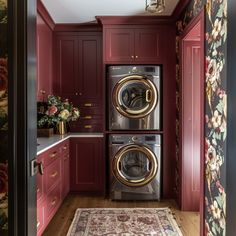 a washer and dryer in a room with red painted walls, wood flooring and floral wallpaper