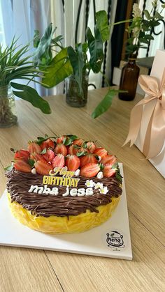 a birthday cake with chocolate frosting and strawberries on top is sitting on a table