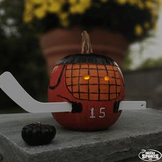 a pumpkin with a hockey stick sticking out of it's side sitting on a ledge