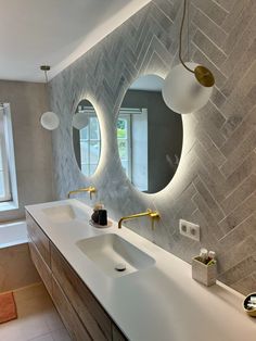 a bathroom with two sinks, mirrors and lights on the wall above them is shown