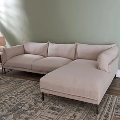 a beige couch sitting on top of a rug next to a lamp