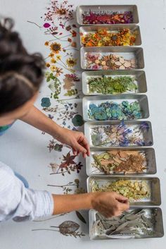 a woman is arranging flowers in trays on the floor