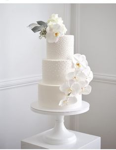 a three tiered white wedding cake with flowers on top