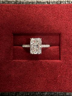 a cushion cut diamond ring in a red velvet box with diamonds on the band and sides