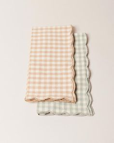 two checkered napkins with scalloped edges, one in beige and the other in white