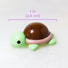 a small toy turtle sitting on top of a white table next to a brown and pink object