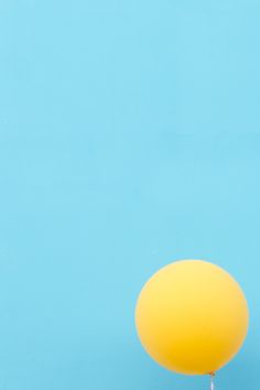 a yellow balloon floating in the air on a blue background