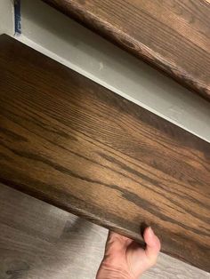 a hand is holding the edge of a piece of wood that has been stained brown