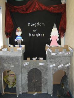 a castle made out of cardboard and some paper on the ground next to a red curtain