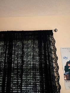 a black lace curtain hanging on the side of a wall next to a movie poster