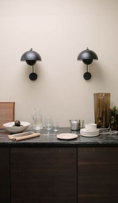 a table with plates and cups on it in front of two wall mounted light fixtures