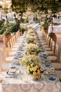 a long table set with blue and white plates, vases filled with yellow flowers