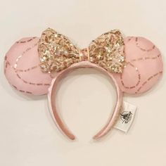 a pink minnie mouse ears with gold sequins and a large bow on top