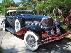 an antique car is parked on the side of the road in front of some palm trees