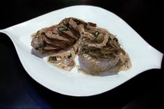 a white plate topped with meat and gravy on top of a black table