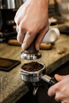 a person is pouring coffee into a grinder